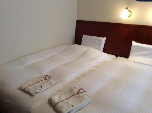 a bed with white sheets and two towels on it at Hotel Sun Queen in Naha