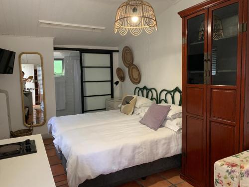 een slaapkamer met een groot wit bed en een kroonluchter bij Courtyard Studio lights and wi fi during load shedding in Stellenbosch