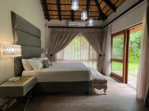 a bedroom with a bed and a large window at Rifumo Luxury Villa in Kruger Park Lodge in Hazyview