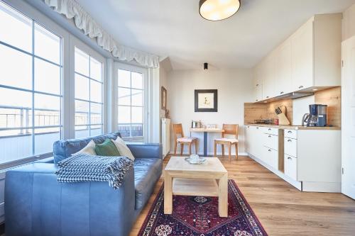 a living room with a blue couch and a table at Ferienwohnung mit Seesicht Grimmershörnbucht in Cuxhaven