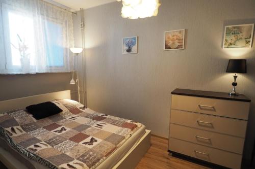 sypialnia z łóżkiem, komodą i oknem w obiekcie KGHN Apartments Tkacka 28 w Szczecinie