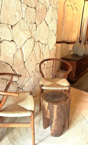 a room with two chairs and a table and a log stool at Alquimia Hotel Boutique in Tulum