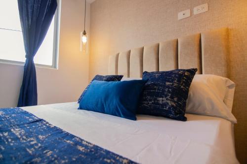 Una cama con almohadas azules y blancas. en Moderno loft en el centro de Pereira, en Pereira