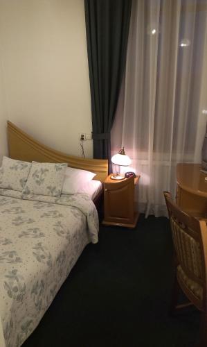 a bedroom with a bed and a table with a lamp at Hotel Bristol in Tarnów