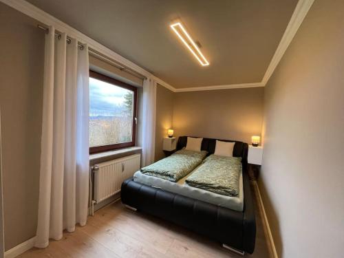 - une chambre avec un lit et une grande fenêtre dans l'établissement Ferienwohnung Leuchtbergblick mit Terrasse und PKW Stellplatz, à Eschwege