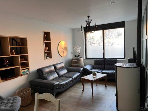 a living room with a leather couch and a table at Villa du parc au cœur de Malo in Dunkerque
