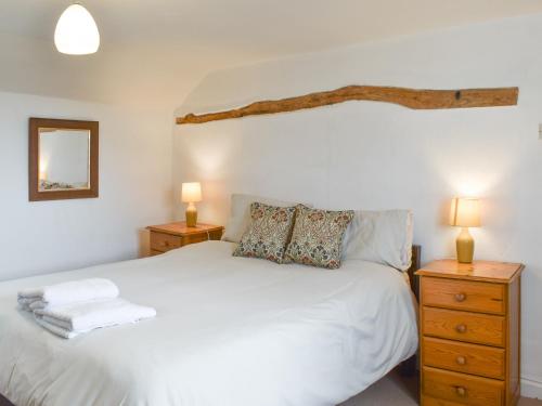 ein Schlafzimmer mit einem weißen Bett und zwei Nachttischen in der Unterkunft Keepers Cottage in Garway