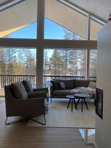 uma sala de estar com sofás e mesas e janelas grandes em Villa Iiris - New Holiday Home em Äkäslompolo
