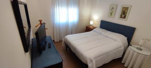 ein Schlafzimmer mit einem großen weißen Bett und einem TV in der Unterkunft Albatros Golf Costa Esuri Ayamonte Huelva in Ayamonte