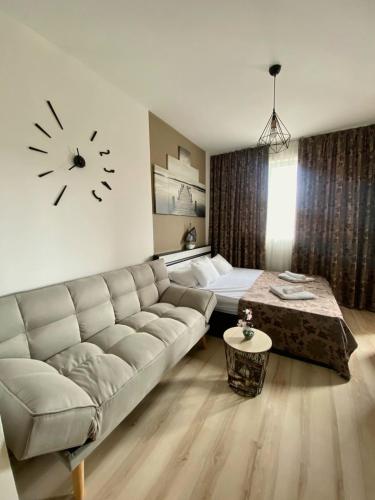 a living room with a couch and a clock on the wall at Апартамент под наем С208 в Афродита Гарденс in Sunny Beach