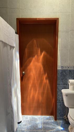 a wooden door in a bathroom with a toilet at Beachfront apartment with swimming pool. One bedroom in Celestún