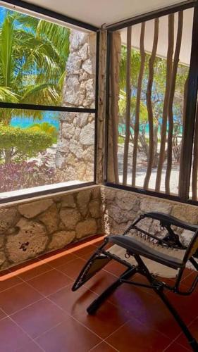 a chair in a room with two large windows at Beachfront apartment with swimming pool. One bedroom in Celestún