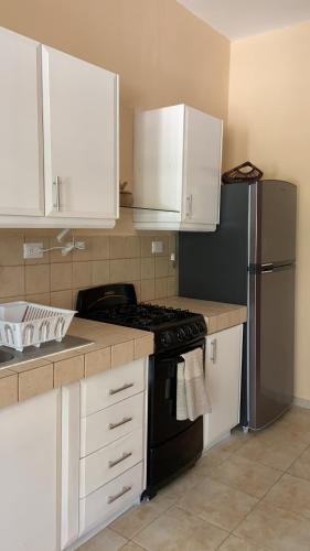 a kitchen with white cabinets and a stove and a refrigerator at Beachfront apartment with swimming pool. One bedroom in Celestún
