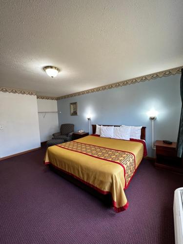 ein Hotelzimmer mit einem großen Bett und einem Stuhl in der Unterkunft Attica Inn in Attica