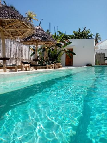 a swimming pool at a resort with blue water at Villa Huruma in Paje