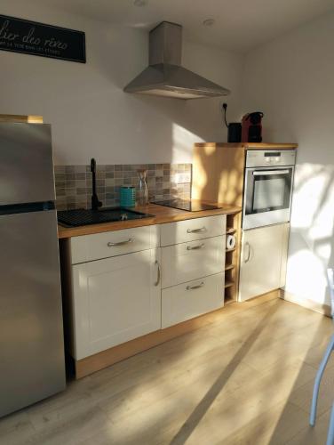 une cuisine avec des armoires blanches, un évier et un réfrigérateur dans l'établissement L'ATELIER DES REVES (gites des oliviers), à La Roque-sur-Cèze