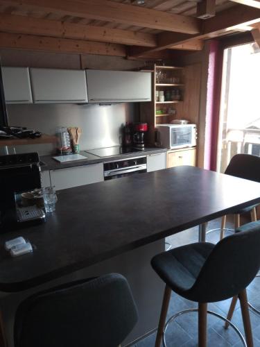 une cuisine avec un grand comptoir noir et des chaises dans l'établissement Appart La Porte des Neiges - Saint Jean de Sixt (La Clusaz, Le Grd Bornand), à Saint-Jean-de-Sixt