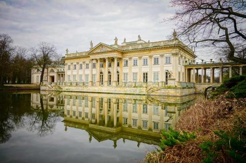 Un gran edificio con su reflejo en el agua. en Apartament Fala Metro SGH Klub Stodoła Parking Parkview Fast Wifi, en Varsovia