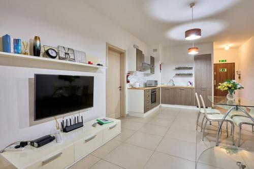 ein Wohnzimmer mit einem großen TV und einem Tisch in der Unterkunft Depiro Point Sliema Luxury Apartment in Sliema