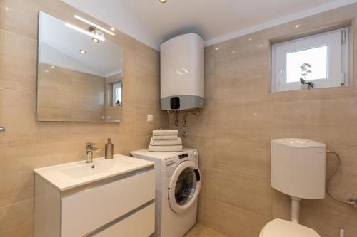 a bathroom with a washing machine and a sink at Apartments Ana in Biograd na Moru