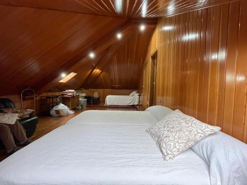 1 cama blanca grande en una habitación con paredes de madera. en Impresionante casa con parcela en la naturaleza, en A Coruña