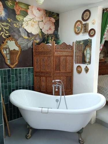 La salle de bains est pourvue d'une baignoire blanche et d'un mur. dans l'établissement L'atelier-chambrette dans le jardin avec salle de bains, sans cuisine, à Trôo