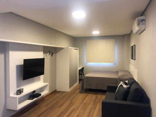 Habitación con cama, sofá y TV. en Villa Leopoldina - Studios de aluguel por temporada no Moinhos de Vento, en Porto Alegre