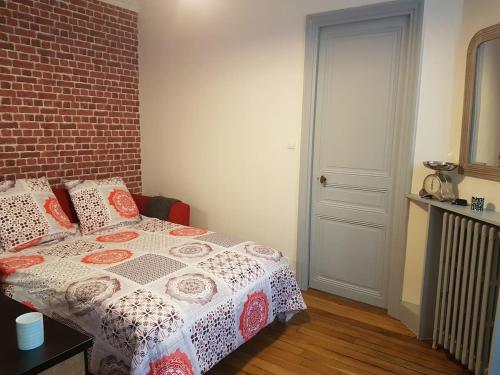 - une chambre avec un lit et un mur en briques dans l'établissement Paris Esprit loft, lumineux, à Aubervilliers