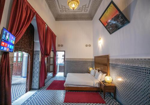 - une chambre avec un lit et une télévision dans l'établissement Riad Dari Fes, à Fès