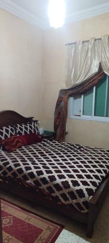 a bed with a black and white comforter in a room at Appartement Fes très propre et calme in Fez