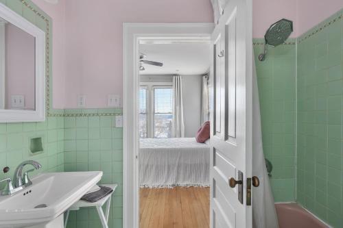a bathroom with green tiles and a sink and a bed at Dubuque's Front Porch, Historic Charmer, Walk Downtown in Dubuque