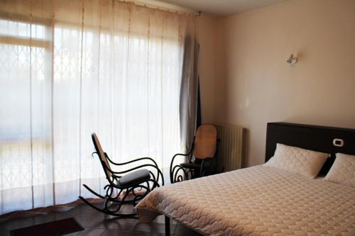 um quarto com uma cama, 2 cadeiras e uma janela em B&B Il Centralino em Legnaro
