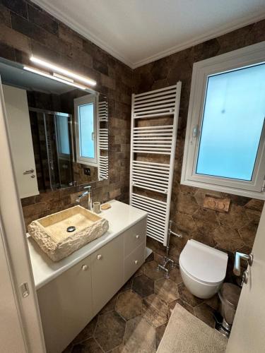 a bathroom with a sink and a toilet and a mirror at Nikole's Villas Cozy 80m2 in Tiros