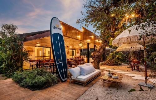 a large surfboard leaning against a building with a couch and chairs at Dolphin Village - Sea Resort By Ran Hotels in Shave Ẕiyyon