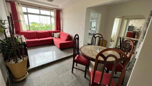 Apartamento no topo da Ilha Porchat في ساو فيسينتي: غرفة معيشة مع أريكة حمراء وطاولة
