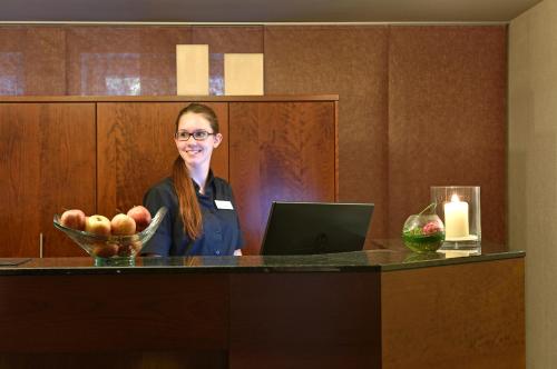 a woman sitting at a counter with a bowl of fruit at Best Western Plus Parkhotel Maximilian Ottobeuren in Ottobeuren