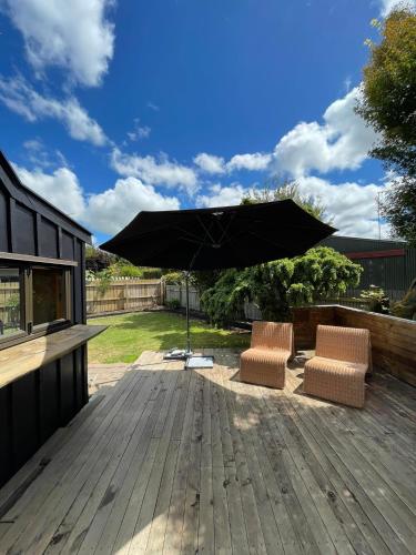 two chairs and an umbrella on a wooden deck at Ski Pad Methven in Methven
