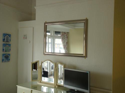 a room with a mirror and a tv on a wall at Spencer Court in Ramsgate