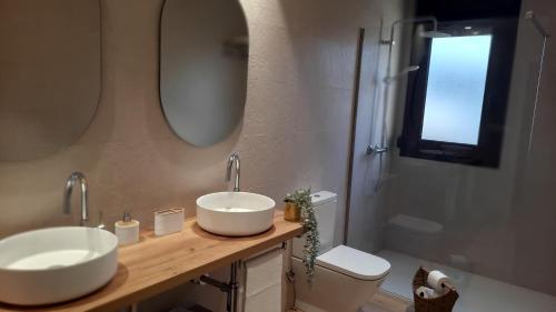 een badkamer met 2 wastafels, een toilet en een spiegel bij Gaiko Etxe Berri in Aizarnazábal