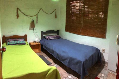 two beds in a bedroom with green walls at Hermoso lugar de descanso en Santa Ana a una cuadra de la playa in Araminda