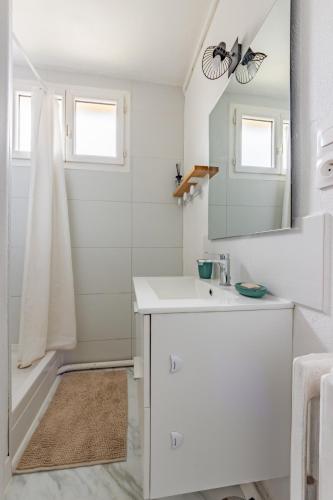 une salle de bain blanche avec un lavabo et un miroir dans l'établissement Le Charmant T3 Côte Pavée parking facile, à Toulouse