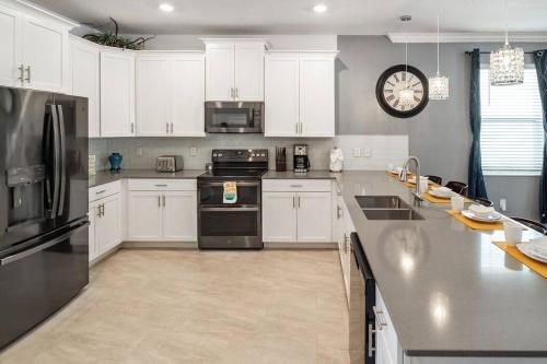 a kitchen with white cabinets and a black refrigerator at Luxury 9BR Villa @ Storey Lake Resort Near Disney in Kissimmee