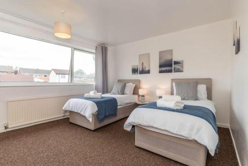 two beds in a bedroom with a large window at Whetstone House in Ketteringham