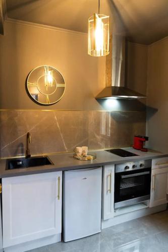 une cuisine avec des placards blancs et une horloge murale dans l'établissement Rêve d'or 3, à Rouen