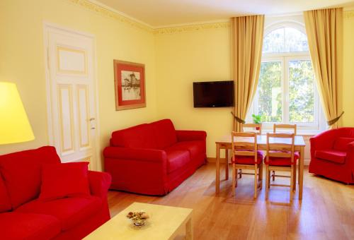 a living room with red furniture and a table at Maloja Palace Residence Engadin-St Moritz CO2-Neutral in Maloja