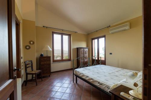 a bedroom with a bed and a chair and windows at Villa Collemancio la soleggiata in Bevagna