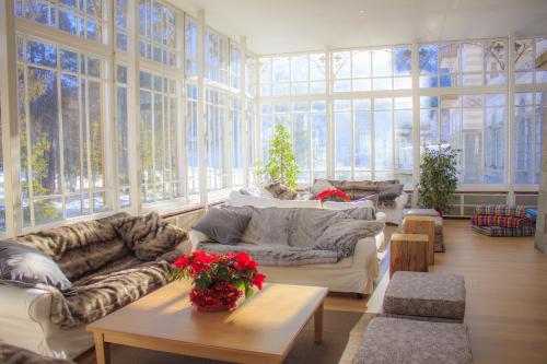 a living room with couches and tables and windows at Maloja Palace Residence Engadin-St Moritz CO2-Neutral in Maloja