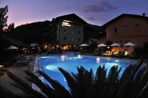 a large swimming pool at a hotel at night at Hotel Florida in Levico Terme