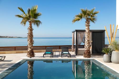 een zwembad met 2 stoelen en palmbomen bij Malibu Imperial Resort in Vir