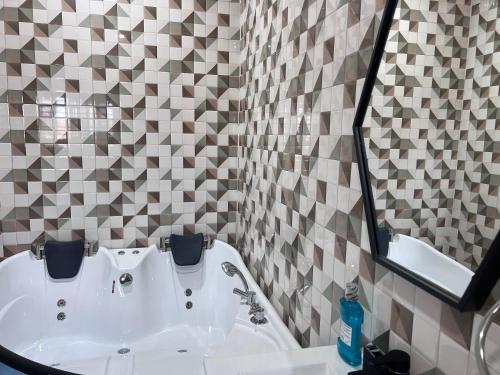La salle de bains est pourvue d'un lavabo blanc et d'un miroir. dans l'établissement T-Roys Apartments, à Accra